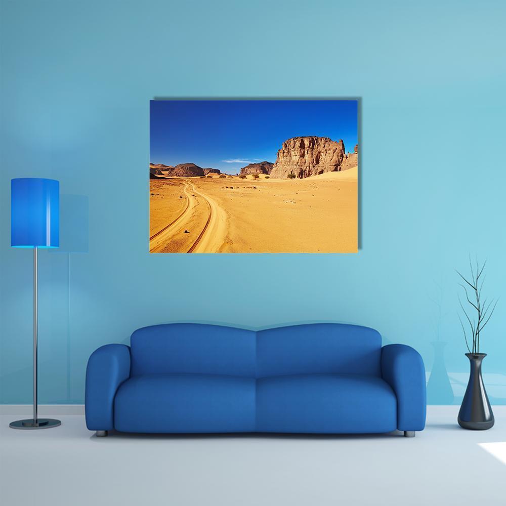 Tire-tracked Desert Road and Rock Formations Canvas Wall Art in brown, yellow and blue, single panel hung on a wall