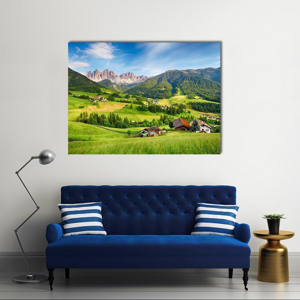 Mountain Village Among Jagged Alpine Peaks Canvas Wall Art in white, green and blue, single panel hung on a wall