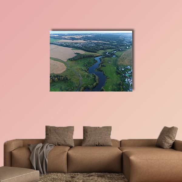 Winding River Over Fields and Village Canvas Wall Art in beige, green and blue, single panel hung on a wall