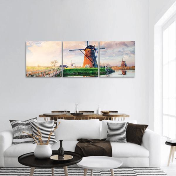 Dutch Windmills with Canal Reflections Panoramic Canvas Wall Art in orange, green and blue, hung on a wall