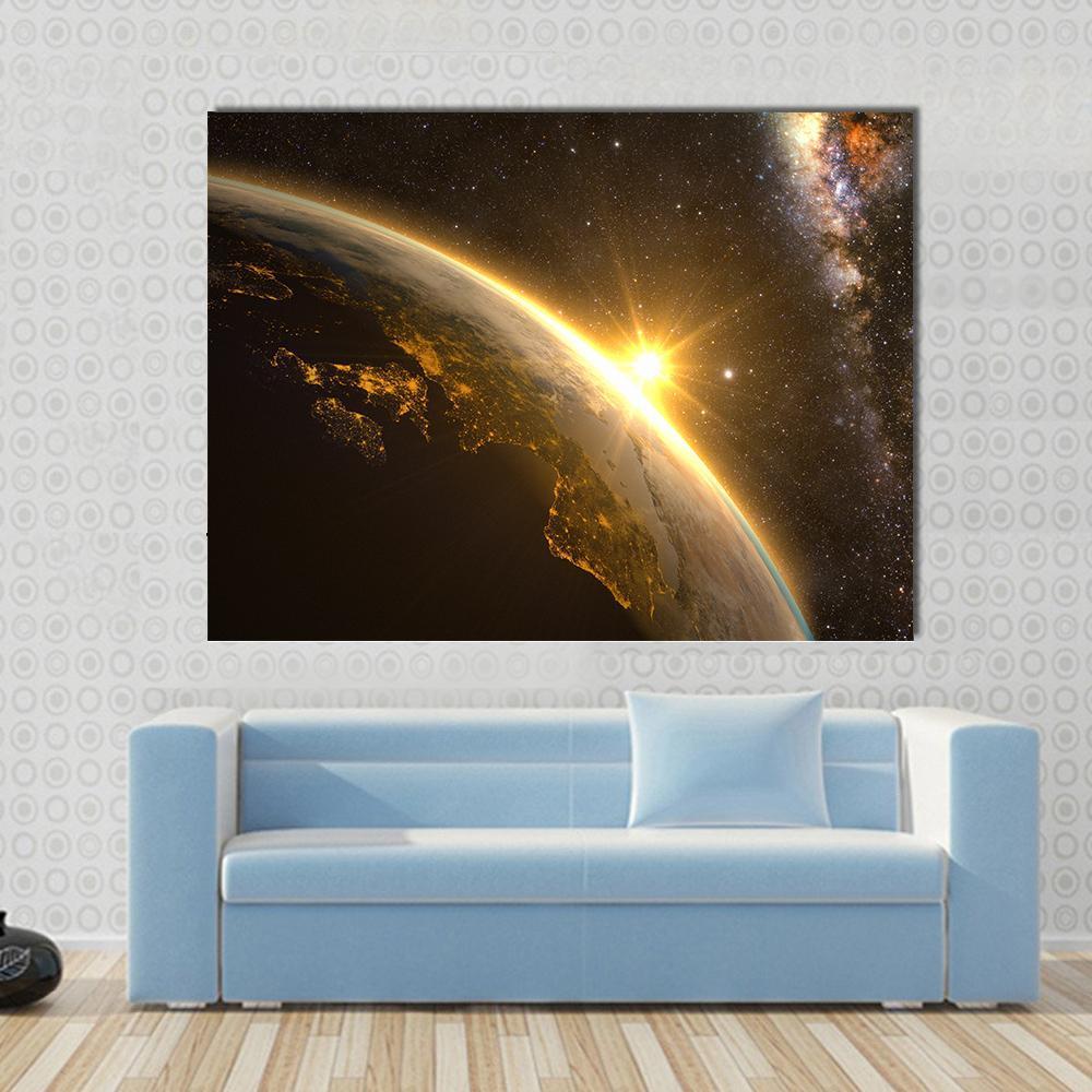 Earth with Spectacular Sunrise Canvas Wall Art in black, orange and yellow, single panel hung on a wall
