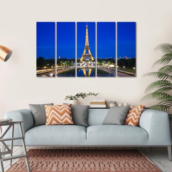Eiffel Tower Illuminated at Twilight Canvas Wall Art in gold, yellow and blue, hung on a wall