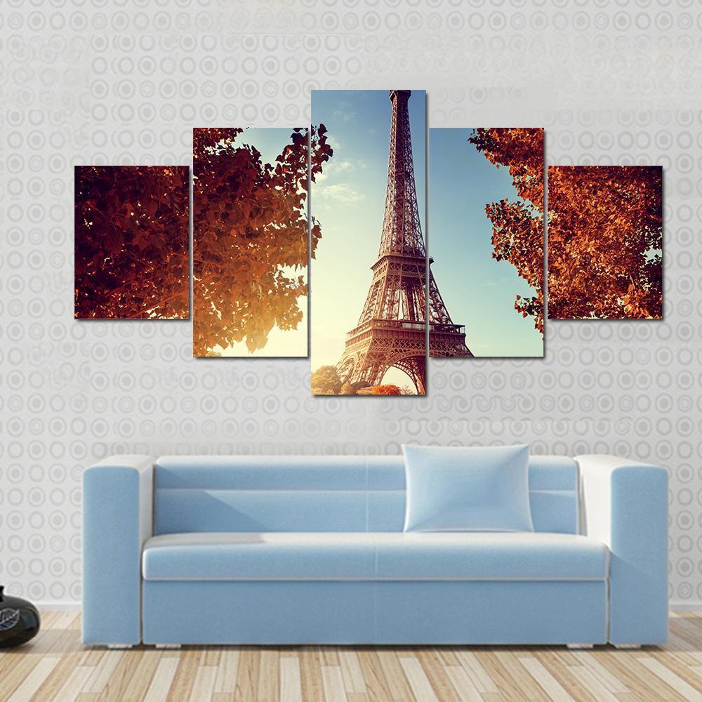 Eiffel Tower in Autumn Canvas Wall Art in brown, orange and blue, 3 panel horizontal set hung on a wall