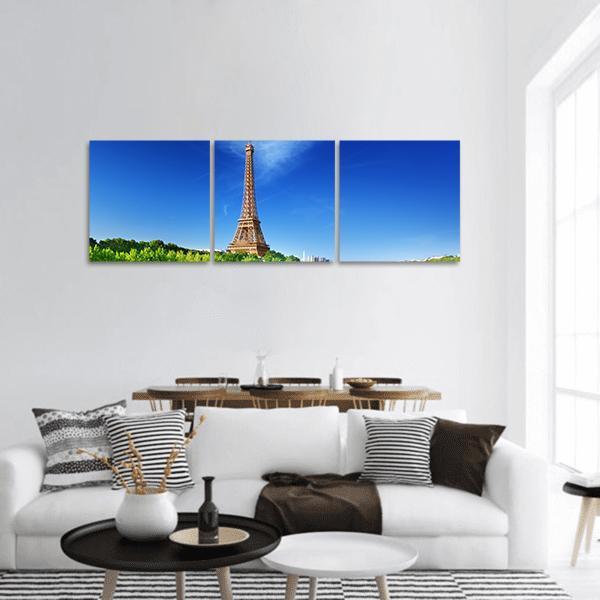 Eiffel Tower Under Blue Sky Panoramic Canvas Wall Art in brown, green and blue, hung on a wall