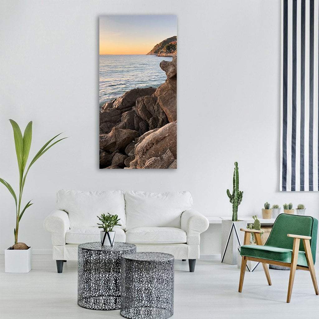 Elba Island Rocky Coast at Sunset Vertical Canvas Wall Art in brown, orange and blue, single vertical panel hung on a wall