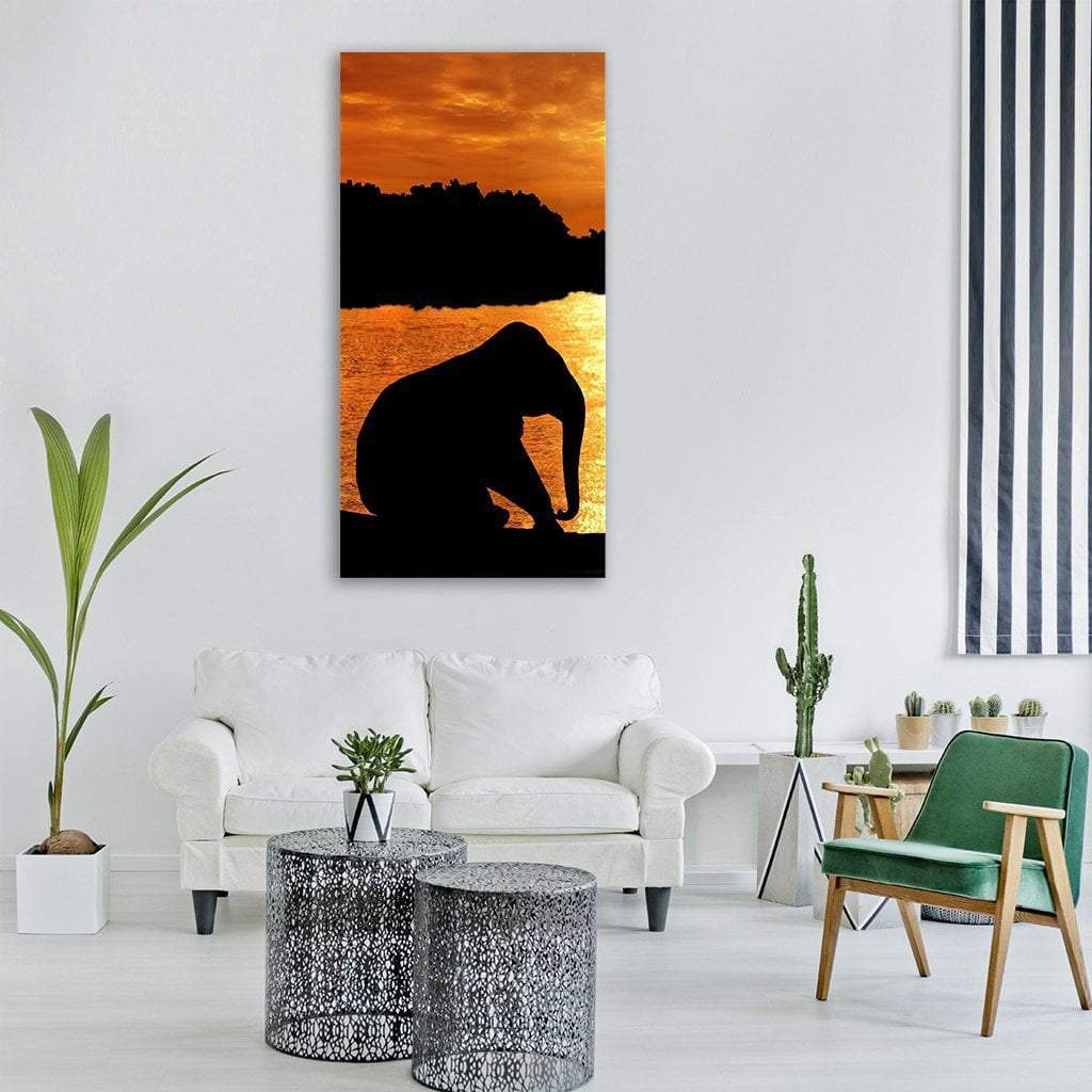 Elephant Silhouette at Golden Sunset Vertical Canvas Wall Art in black, orange and yellow, single vertical panel hung on a wall