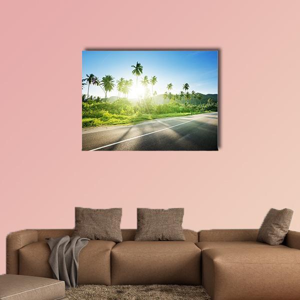 Sunlit Road Through Jungle Canvas Wall Art in gray, green and blue, single panel hung on a wall
