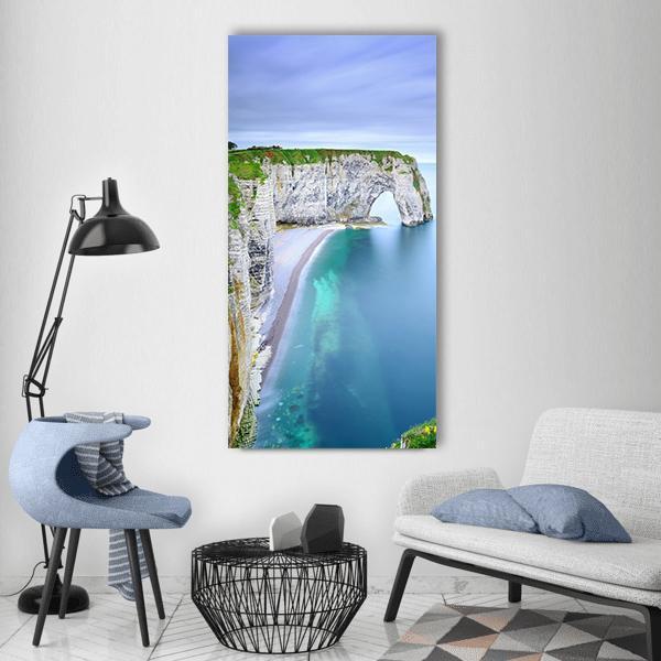 La Manneporte Coastal Rock Arch Vertical Canvas Wall Art in gray, green and blue, single vertical panel hung on a wall
