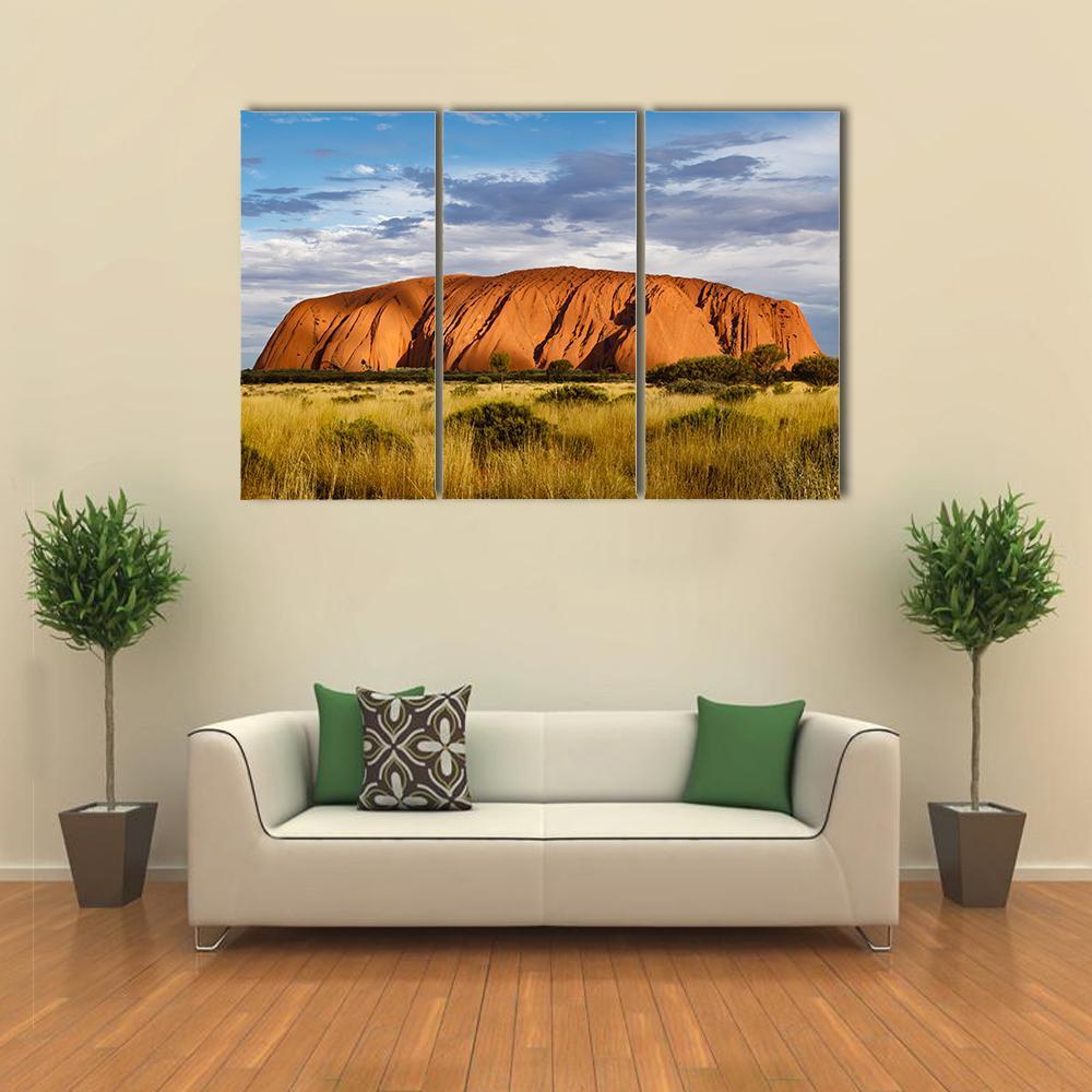Uluru Red Sandstone Monolith Canvas Wall Art in orange, yellow and blue, 3 panel horizontal set hung on a wall