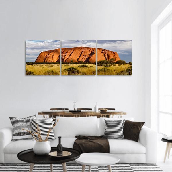 Red Sandstone Monolith Over Golden Grassland Panoramic Canvas Wall Art in red, orange and yellow, hung on a wall