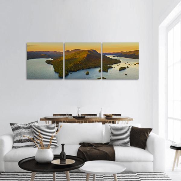 Autumn Foliage Over Island Lake Panoramic Canvas Wall Art in orange, green and blue, hung on a wall