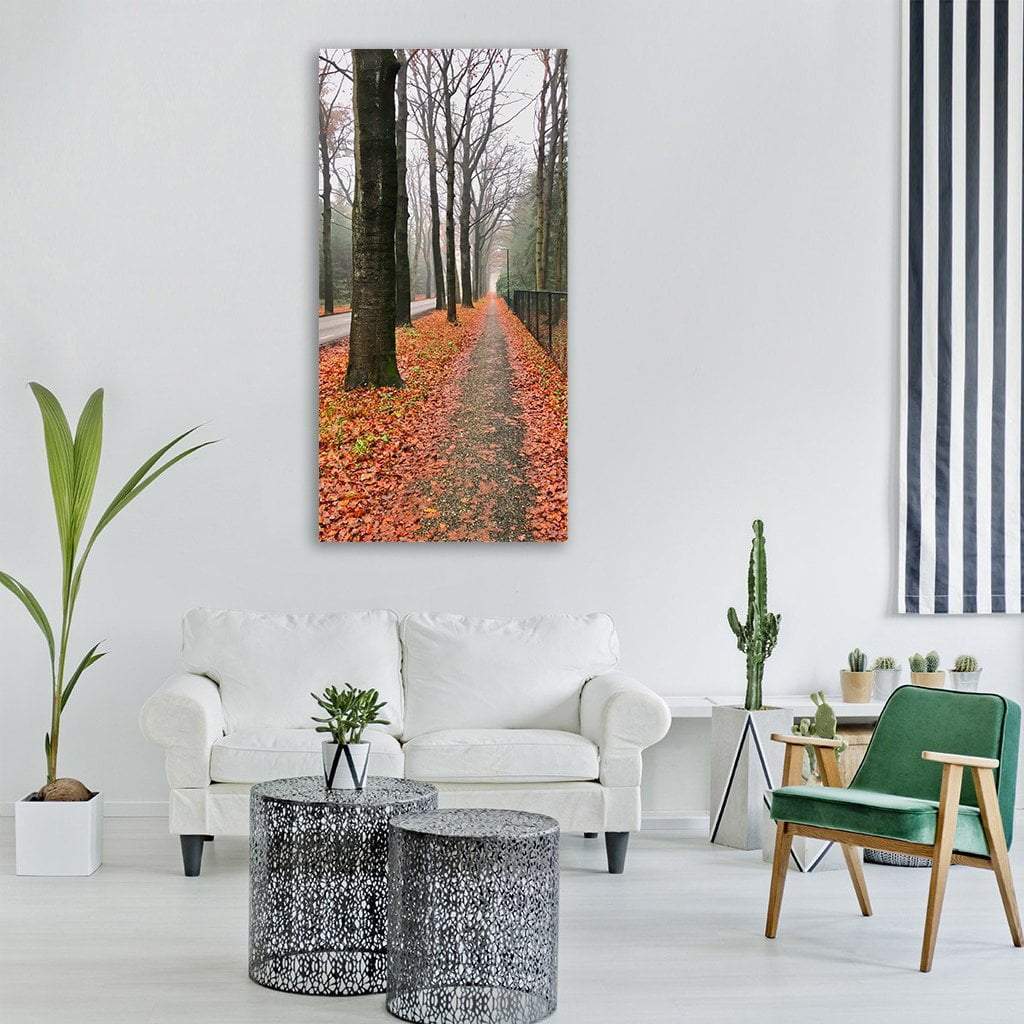 Autumn Road Through Bare Trees Vertical Canvas Wall Art in gray, brown and orange, single vertical panel hung on a wall