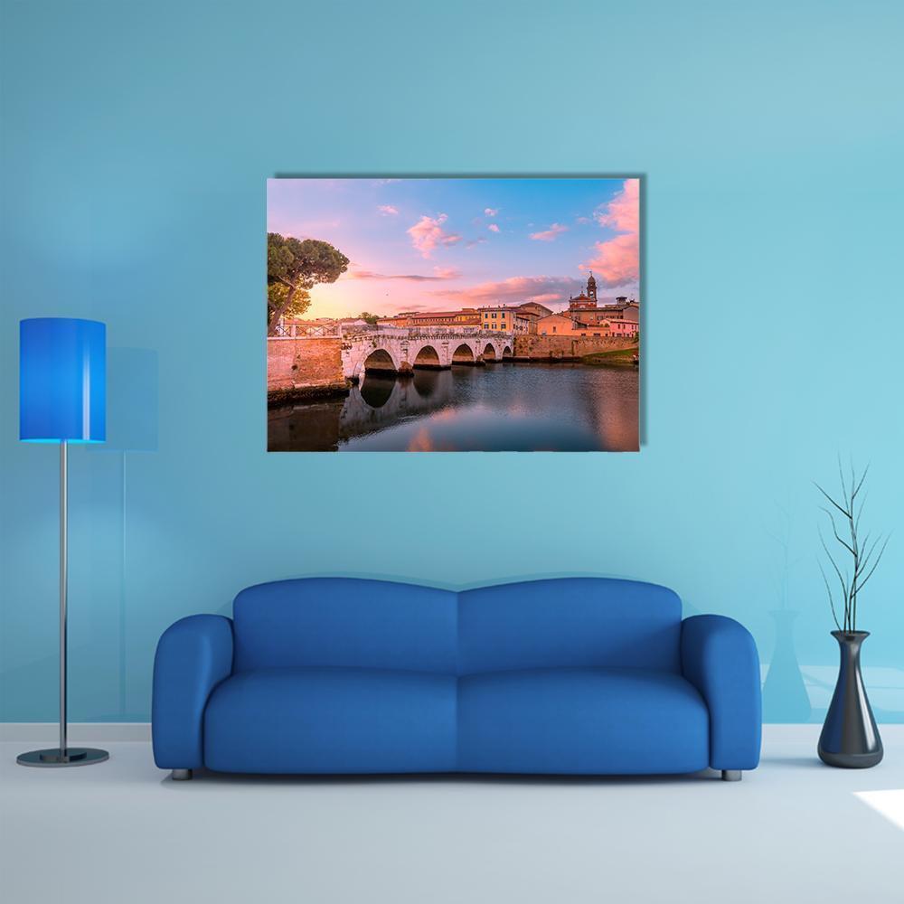 Arched Bridge Reflecting at Sunset Canvas Wall Art in orange, blue and pink, single panel hung on a wall