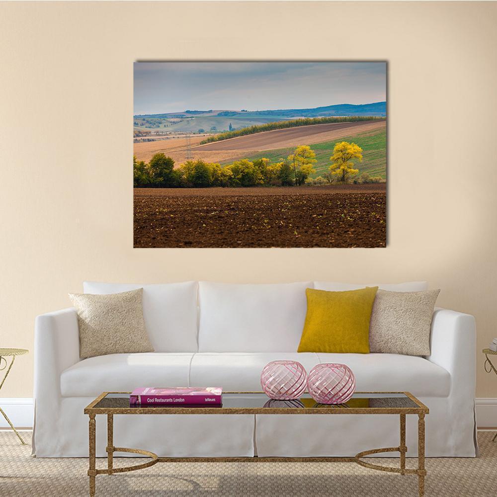 Farm Landscape with Plowed Field Canvas Wall Art in brown, green and blue, single panel hung on a wall