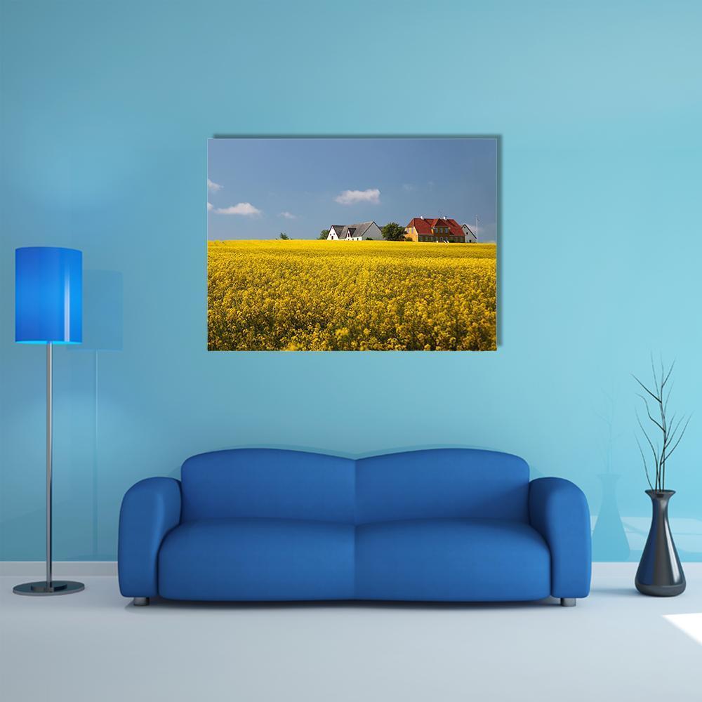 Farmhouses in a Yellow Flower Field Canvas Wall Art in yellow and blue, single panel hung on a wall
