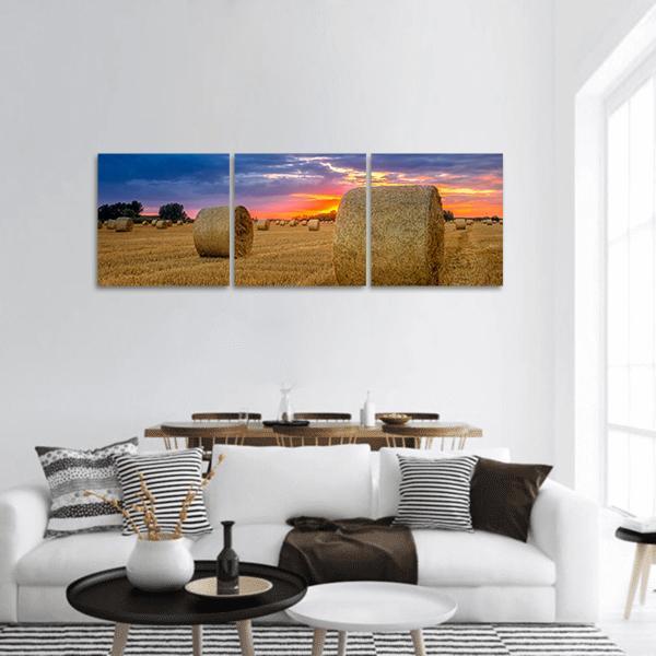 Sunset Hay Bale in Harvest Field Panoramic Canvas Wall Art in orange, yellow and blue, hung on a wall