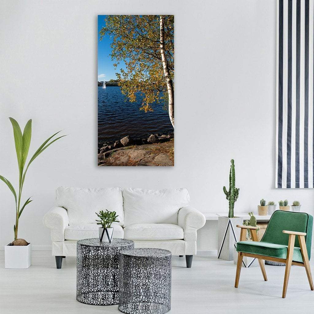 Finnish Lake with Birch Tree and Fountain Vertical Canvas Wall Art in yellow, green and blue, single vertical panel hung on a wall