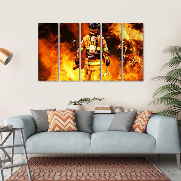 Firefighter Amid Intense Flames Canvas Wall Art in black, orange and yellow, hung on a wall