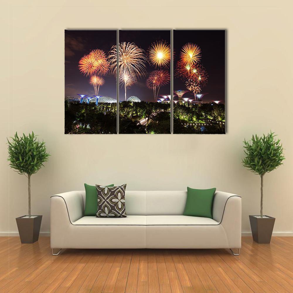 Fireworks Over Illuminated Gardens Canvas Wall Art in black, gold and orange, 3 panel horizontal set hung on a wall