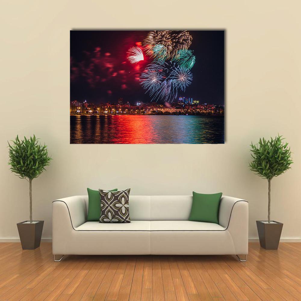 City Fireworks Over River at Night Canvas Wall Art in black, red and multicolor, single panel hung on a wall