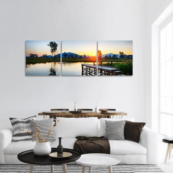 Sunrise Over Fishing Jetty Panoramic Canvas Wall Art in orange, yellow and blue, hung on a wall