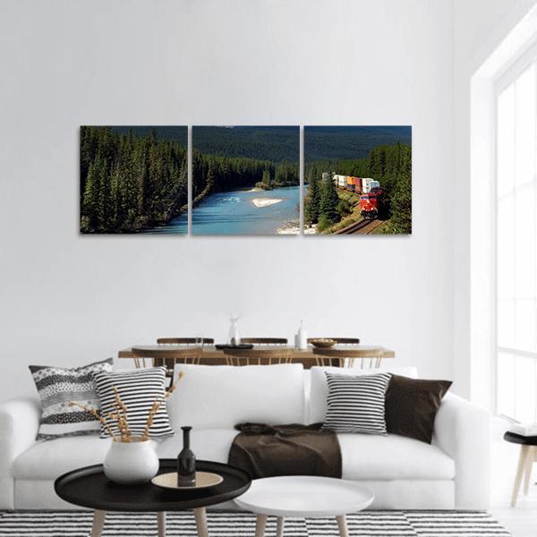 Freight Train Along Pine River Panoramic Canvas Wall Art in brown, green and blue, hung on a wall