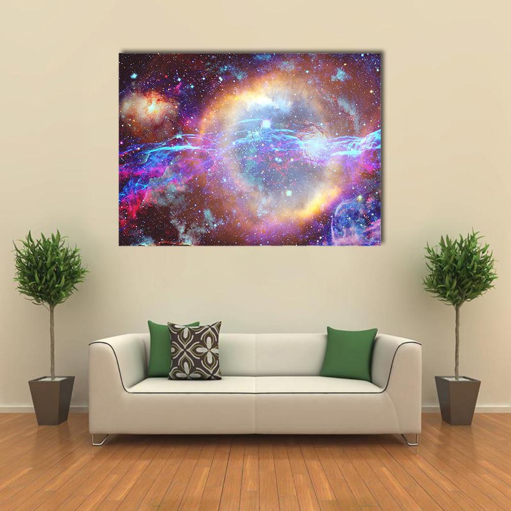 Galaxy Nebula with Bright Central Ring Canvas Wall Art in orange, blue and purple, single panel hung on a wall