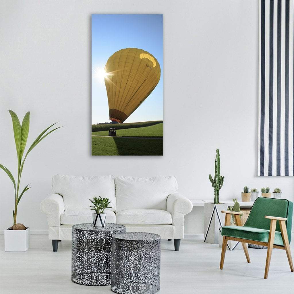 Yellow Hot Air Balloon Over Green Field Vertical Canvas Wall Art in yellow, green and blue, single vertical panel hung on a wall