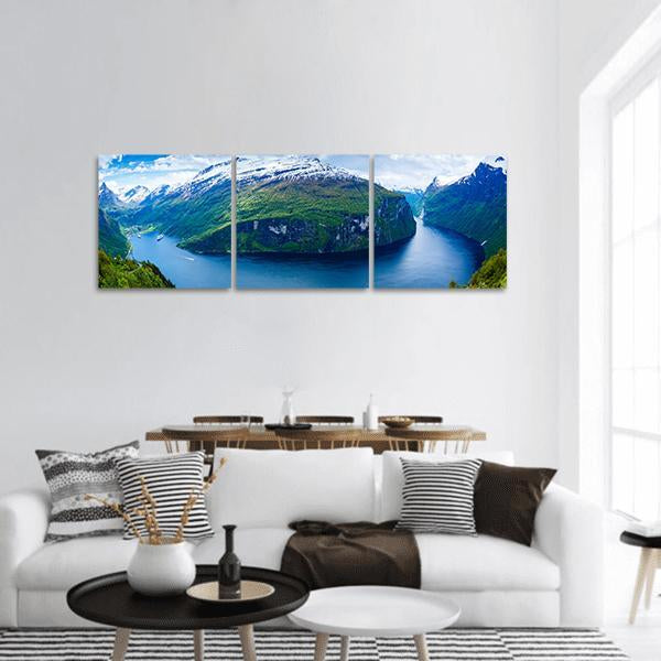 Geiranger Fjord with Boat and Snow Peaks Panoramic Canvas Wall Art in white, green and blue, hung on a wall