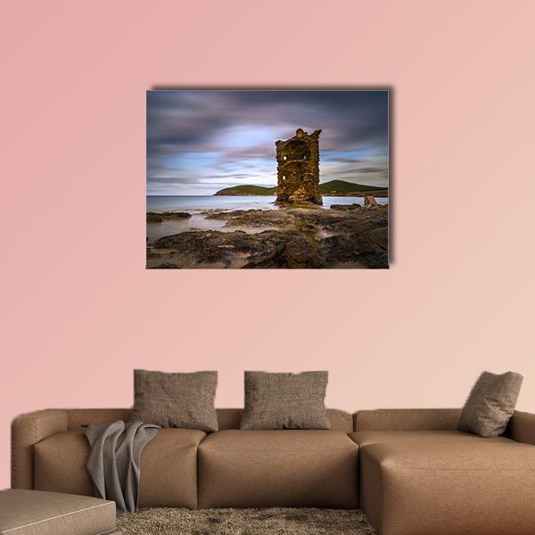 Crumbling Stone Tower on Rocky Coast Canvas Wall Art in gray, brown and blue, single panel hung on a wall