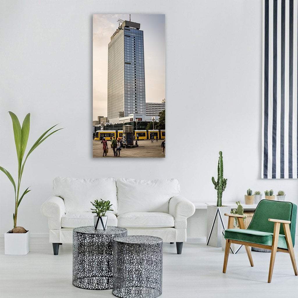 Yellow Tram at Park Inn Alexanderplatz Vertical Canvas Wall Art in gray, yellow and blue, single vertical panel hung on a wall