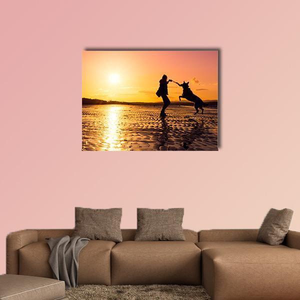 Girl Playing with Dog at Sunset Beach Canvas Wall Art in black, orange and yellow, single panel hung on a wall