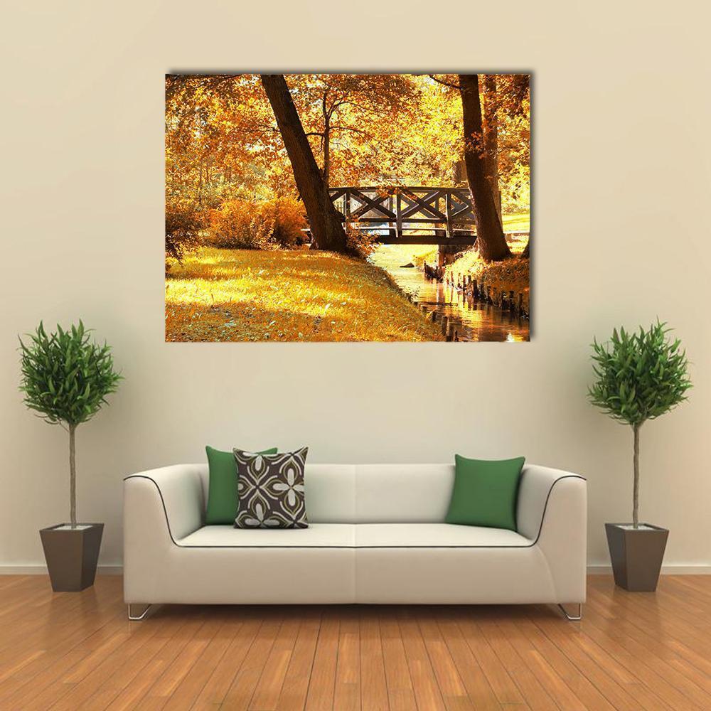 Autumn Bridge Over Golden Stream Canvas Wall Art in brown, gold and yellow, single panel hung on a wall