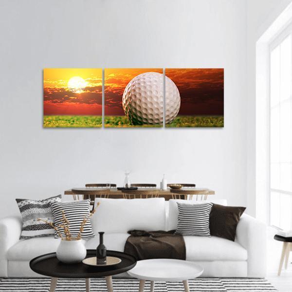 Golf Ball at Sunset Panoramic Canvas Wall Art in orange, yellow and green, hung on a wall