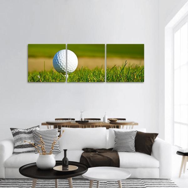 Close-up Golf Ball on Tee Panoramic Canvas Wall Art in white, yellow and green, hung on a wall