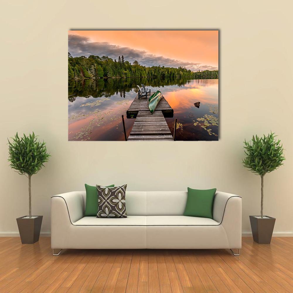 Green Canoe and Adirondack Chairs on Lake Canvas Wall Art in brown, orange and green, single panel hung on a wall