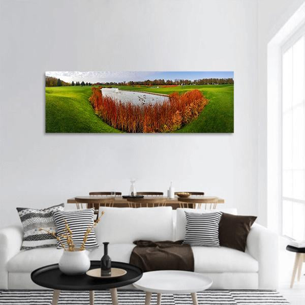 Autumn Pond on Golf Course Panoramic Canvas Wall Art in orange, green and blue, hung on a wall
