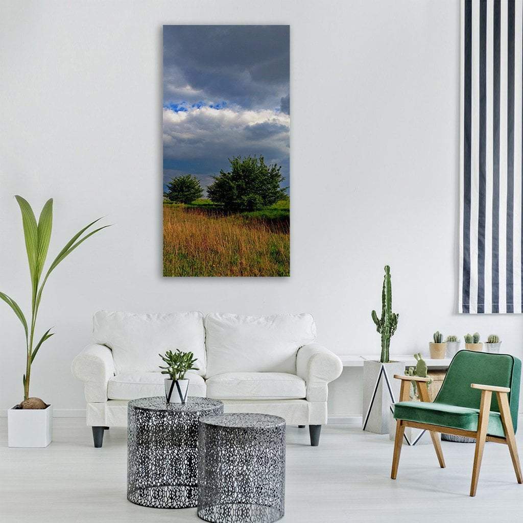 Spring Field with Stormy Sky Vertical Canvas Wall Art in gray, green and blue, hung on a wall