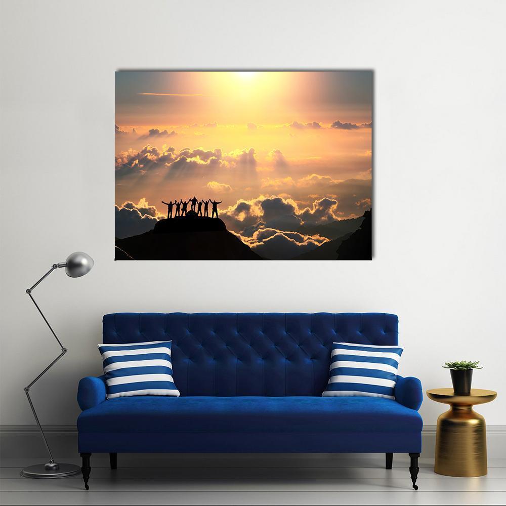 Silhouetted Group on Mountain Peak Canvas Wall Art in black, orange and yellow, single panel hung on a wall