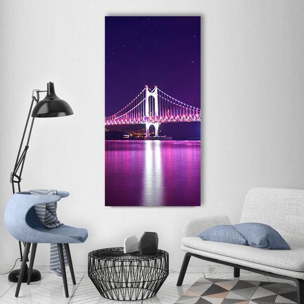 Gwangan Bridge at Night Vertical Canvas Wall Art in navy, purple and pink, single vertical panel hung on a wall