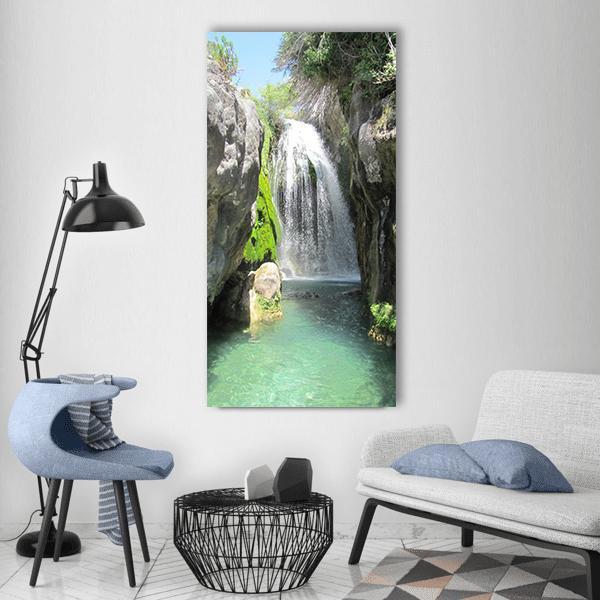 Waterfall Among Mossy Rocks Vertical Canvas Wall Art in gray, green and blue, single vertical panel hung on a wall