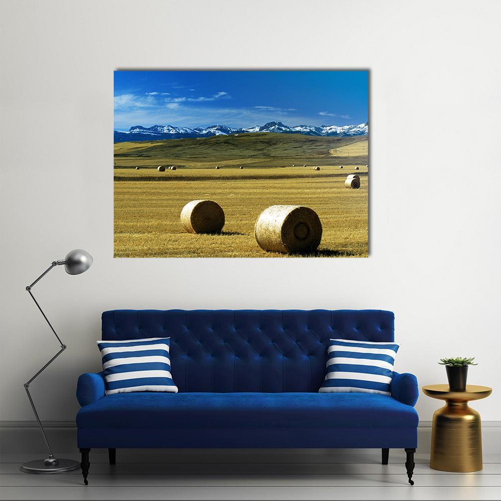 Hay Bales with Snow-capped Mountains Canvas Wall Art in brown, yellow and blue, single panel hung on a wall
