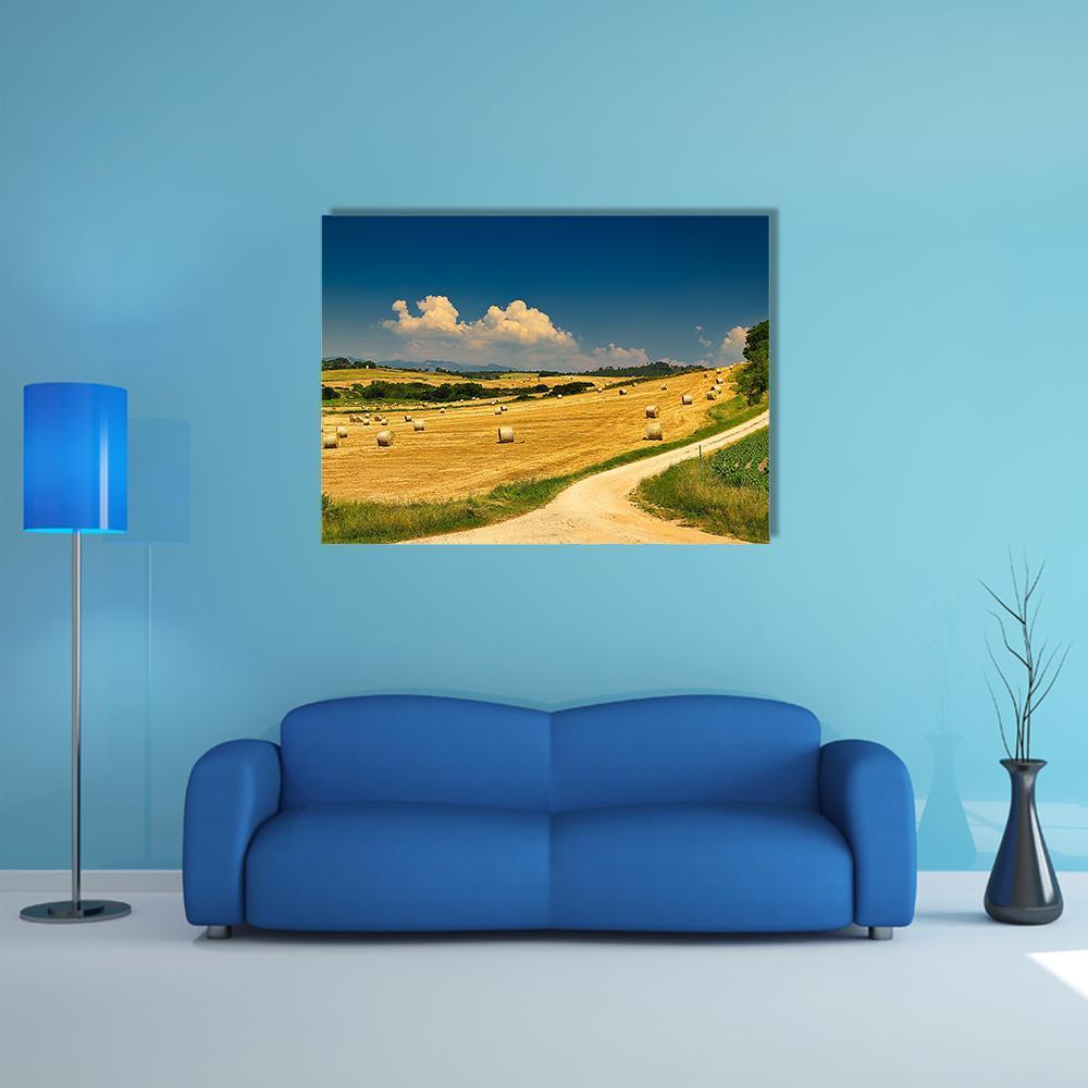 Hay Bales on Harvested Field Canvas Wall Art in yellow, green and blue, single panel hung on a wall