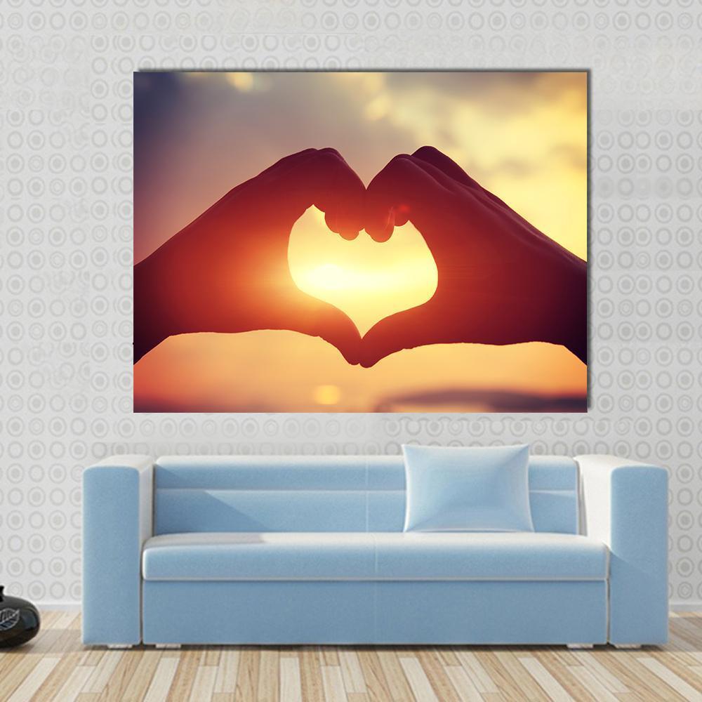 Hands Forming Heart at Sunset Canvas Wall Art in black, orange and yellow, single panel hung on a wall