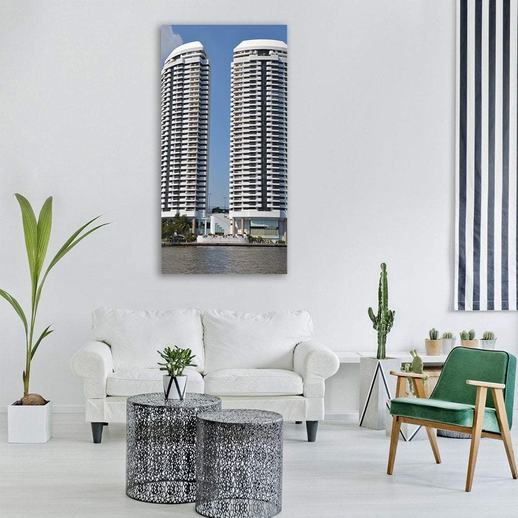 High-rise Hotel Twin Towers on Riverfront Vertical Canvas Wall Art in white, gray and blue, single vertical panel hung on a wall
