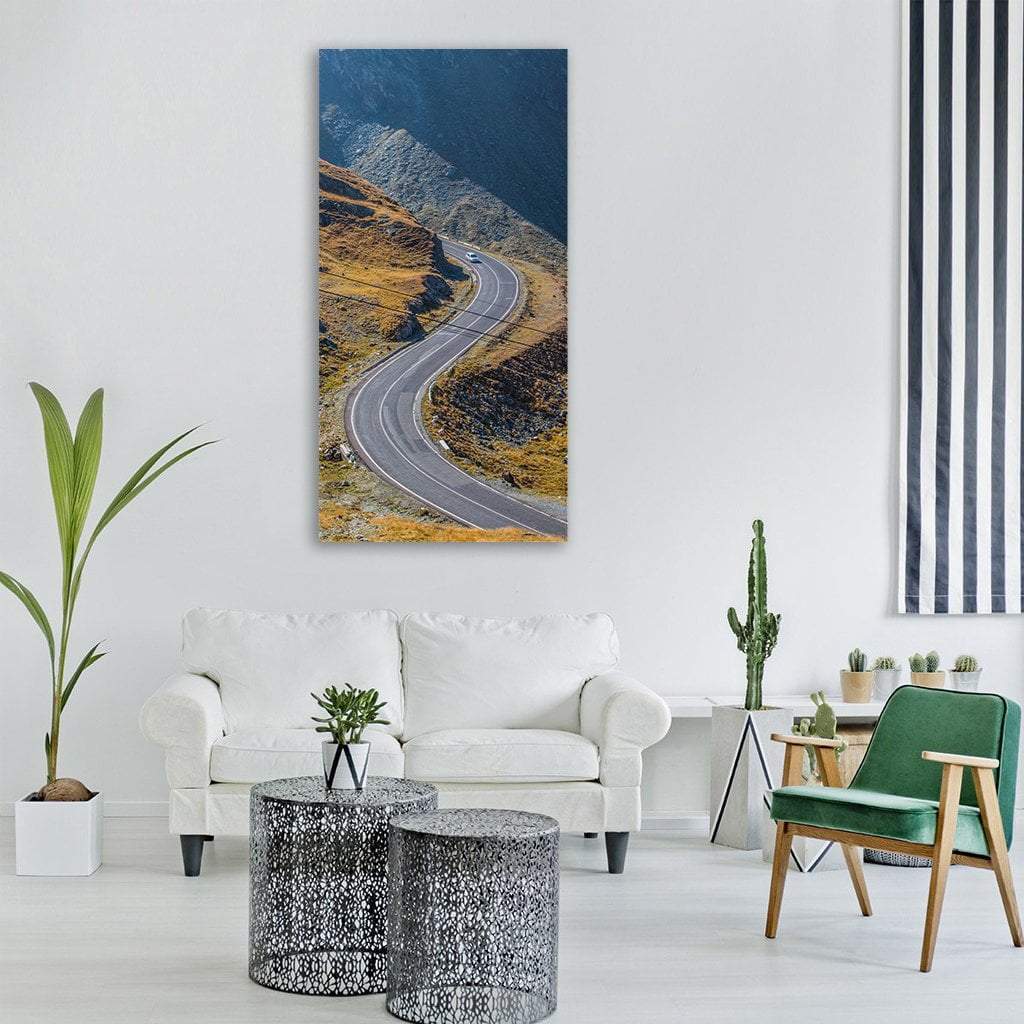 Winding Alpine Road with Distant Car Vertical Canvas Wall Art in gray, yellow and blue, single vertical panel hung on a wall