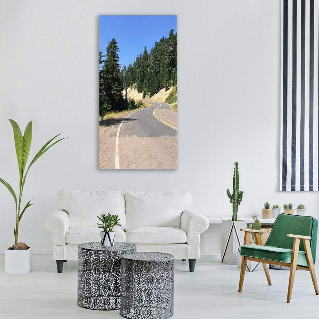 Winding Mountain Road Through Evergreen Forest Vertical Canvas Wall Art in gray, green and blue, single vertical panel hung on a wall