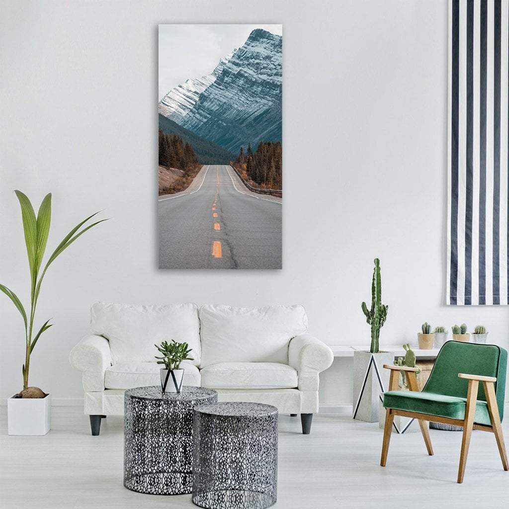 Paved Mountain Road Through Pines Vertical Canvas Wall Art in white, gray and blue, single vertical panel hung on a wall
