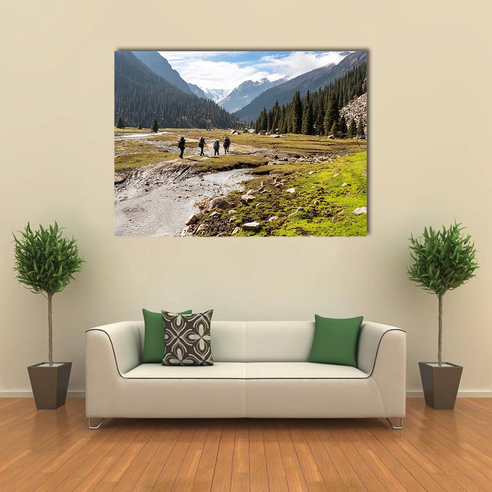 Hikers by Winding River in Snow-capped Valley Canvas Wall Art in gray, green and blue, single panel hung on a wall