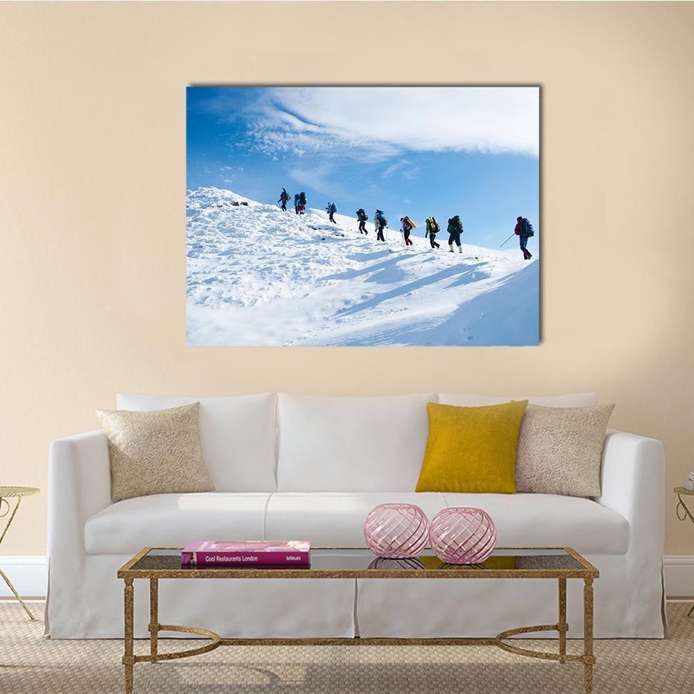 Hikers Ascending Snowy Mountain Canvas Wall Art in white and blue, single panel hung on a wall